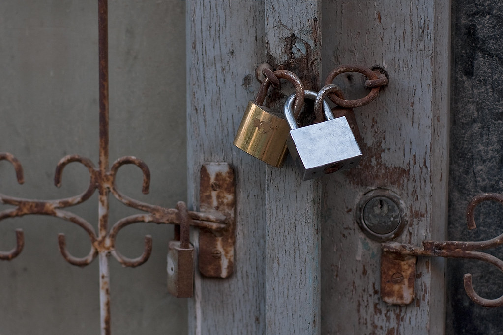 Couple of metallic padlocks on old door frame